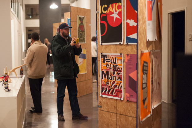 Man takes photo at the Cuban Poster Design Exhibit at Atomicdust