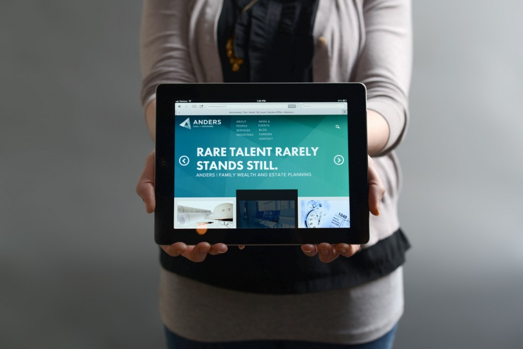 Designer at Atomicdust holding the new Anders CPA website on an iPad