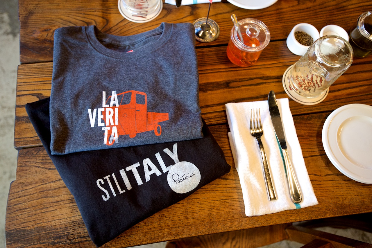 Atomicdust Designs Italian-Inspired Shirts on a table at Pastaria