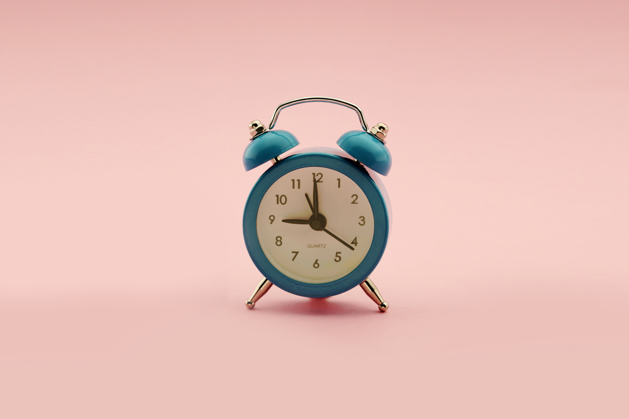 A vintage alarm clock on a pink background