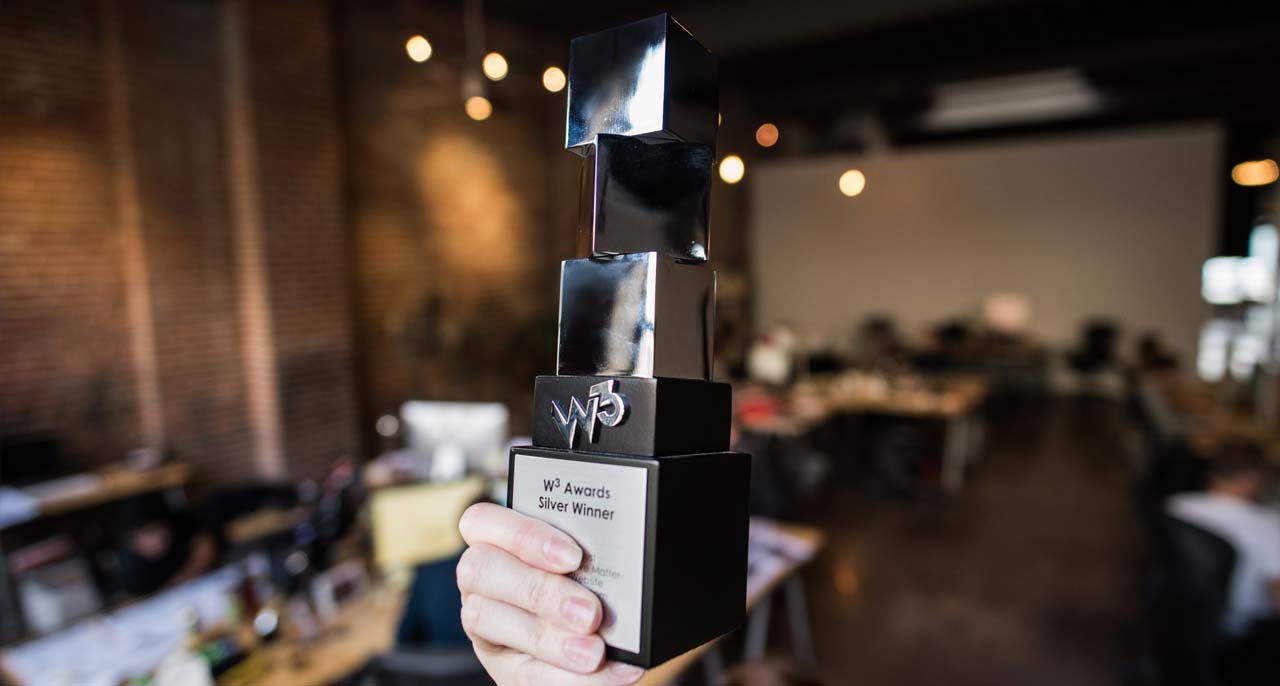 Atomicdust designer holding a W3 trophy in the office