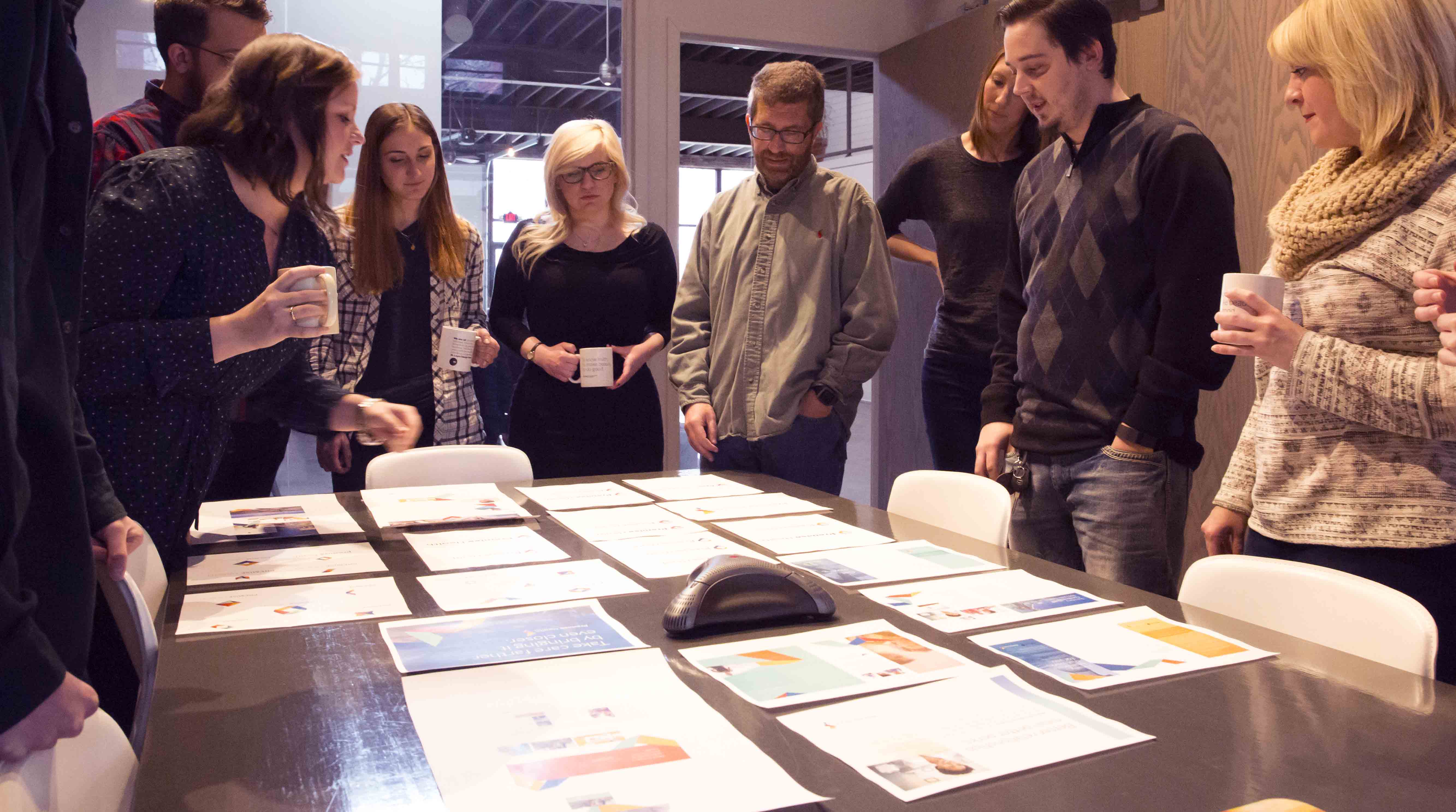 Creatives at Atomicdust looking at designs and discussing a branding project around a table