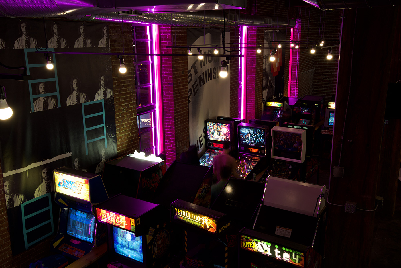 The neon lights and grunge banners above the arcade cabinets at Start Bar