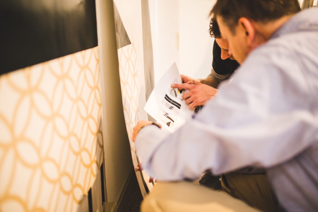 Men installing the branded mural at Anew