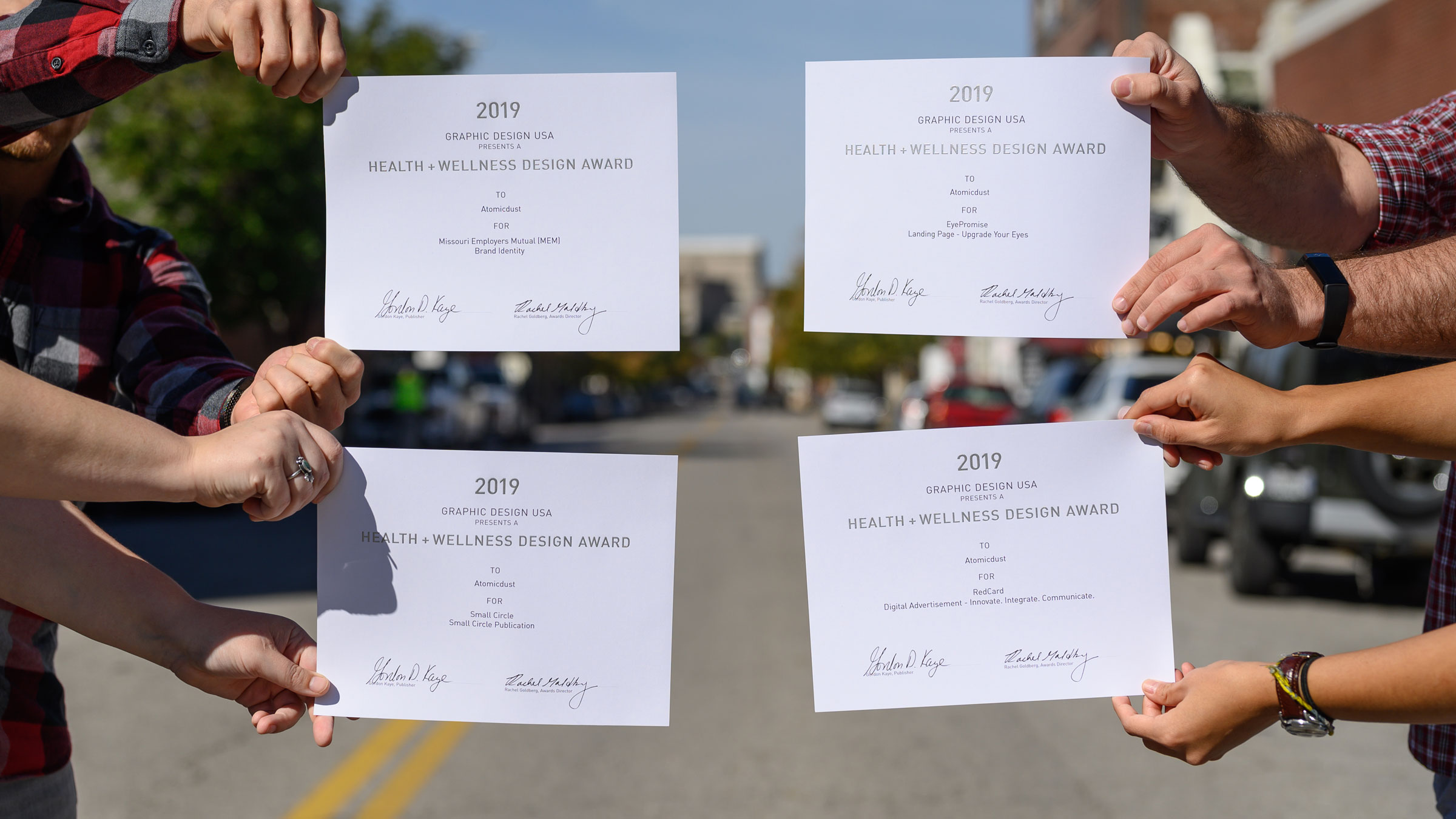 Atomicdust team members holding GDUSA Health + Wellness Design Awards certificates