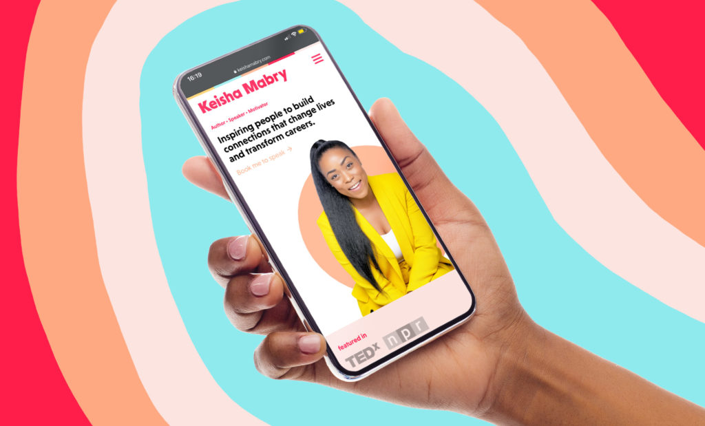 A hand holds an iPhone with Keisha Mabry's mobile-responsive website on the screen
