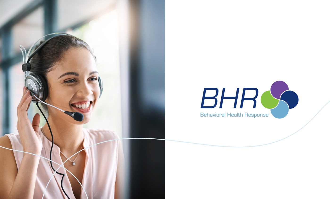 A Behavioral Health Response crisis hotline employee talks on the phone next to a BHR logo