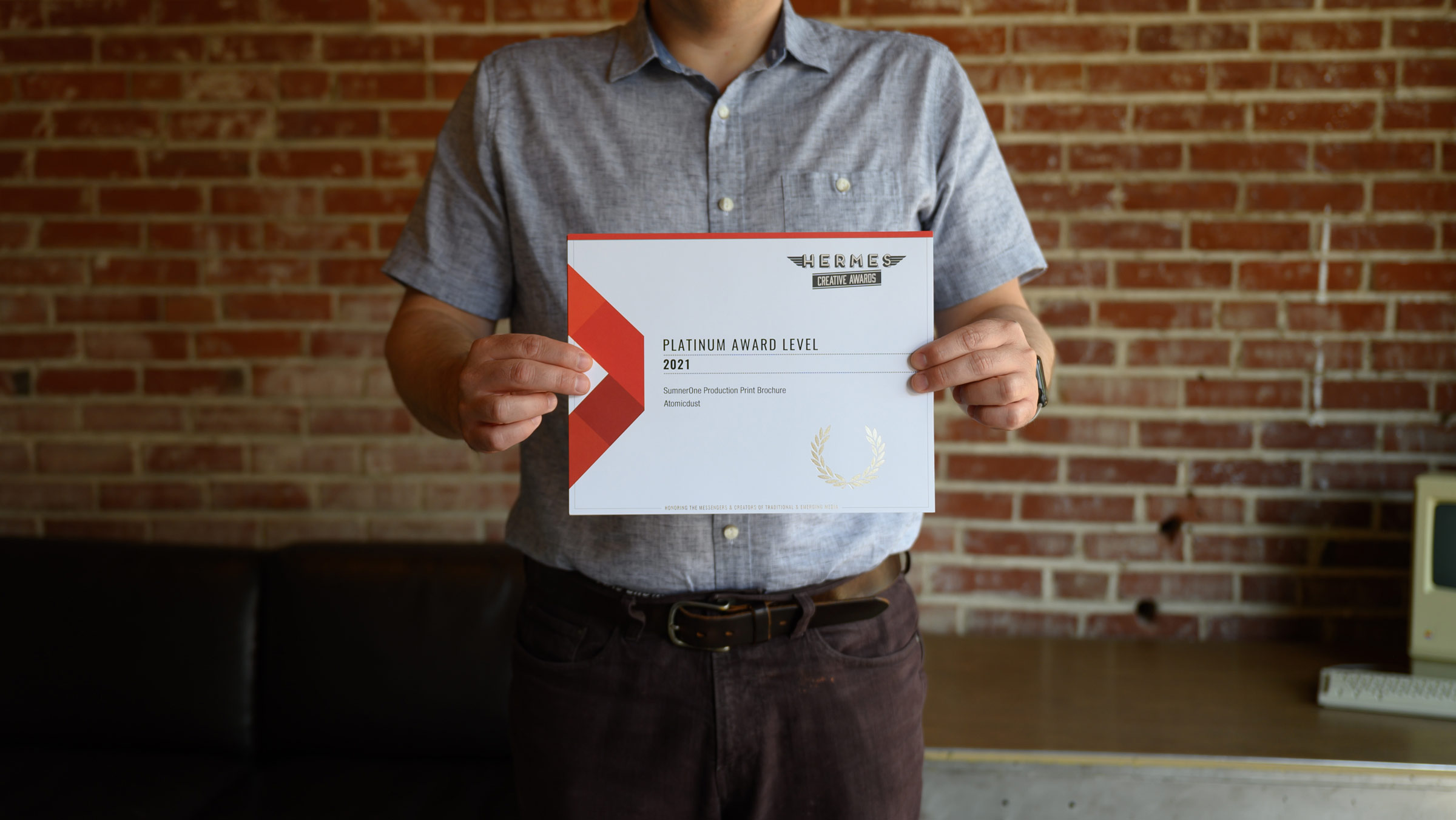 An Atomicdust team member holds the Hermes Creative Awards certificates