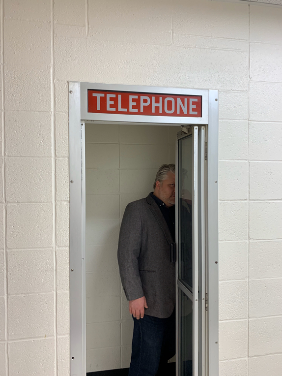 Atomicdust Partner/Creative Director Mike Spakowski stands in a vintage telephone booth on Cor Jesu's campus