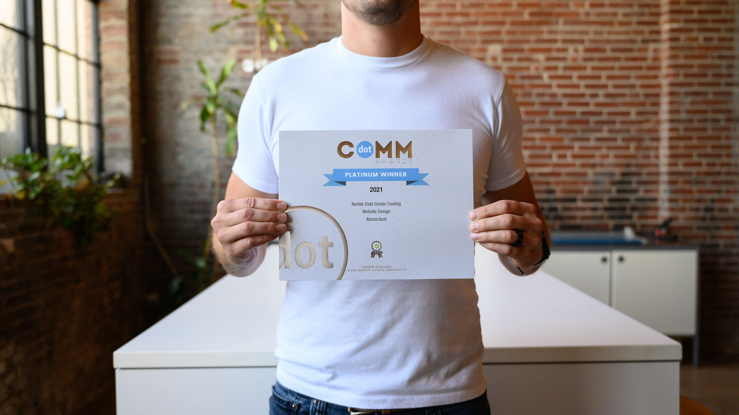 An Atomicdust team member holds the dotCOMM Awards certificates