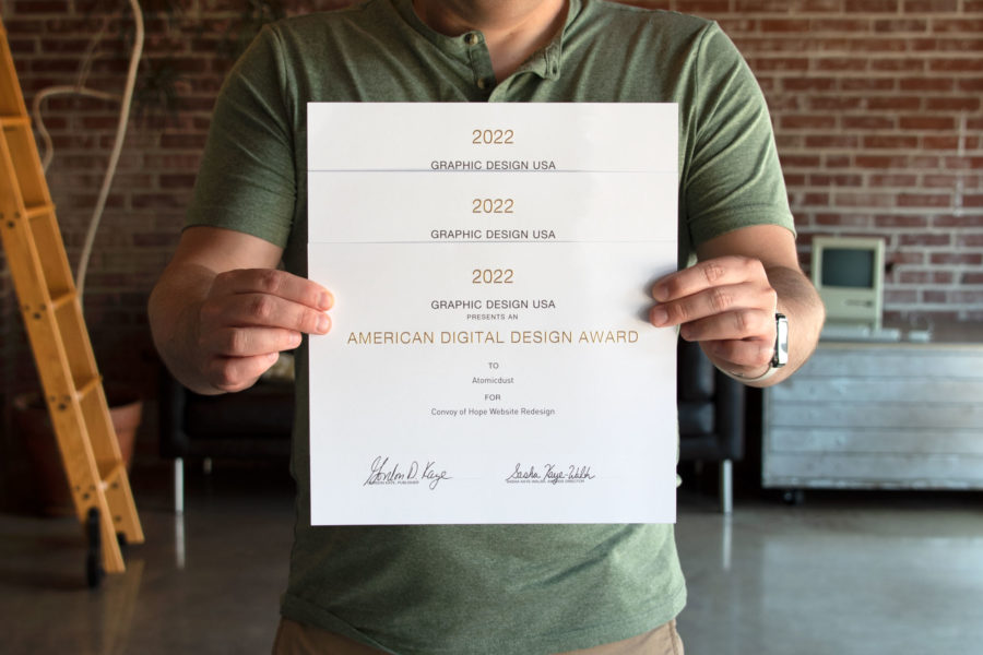 An Atomicdust team member holds this year's GDUSA Digital Design Awards certificates