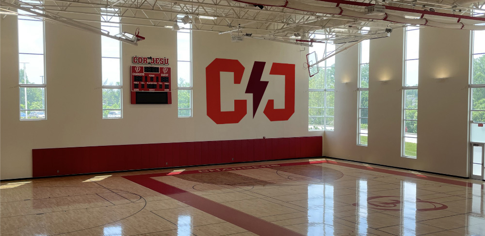 Mockup showing the new Cor Jesu athletics brand on the gym walls