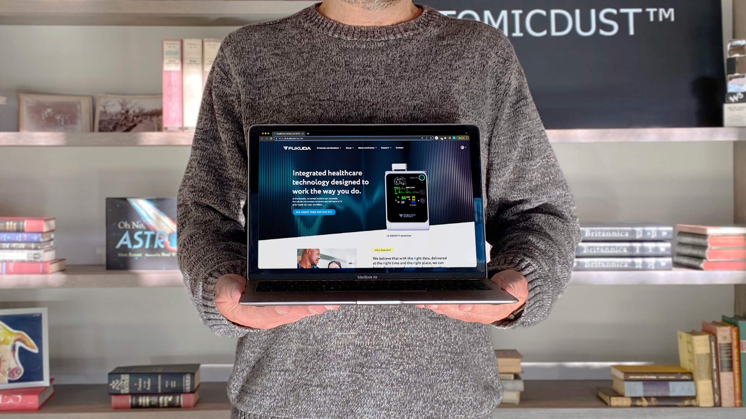 An Atomicdust team member holds a laptop with a B2B website design on the screen