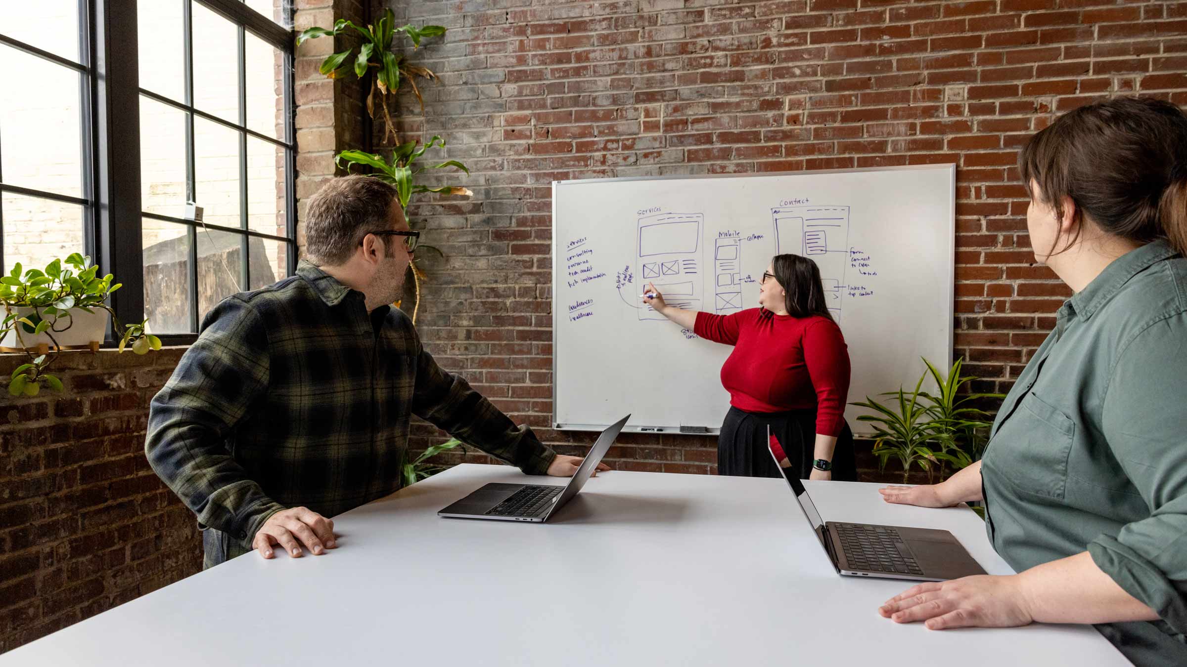 The Atomicdust team discusses a website design project with notes on a whiteboard