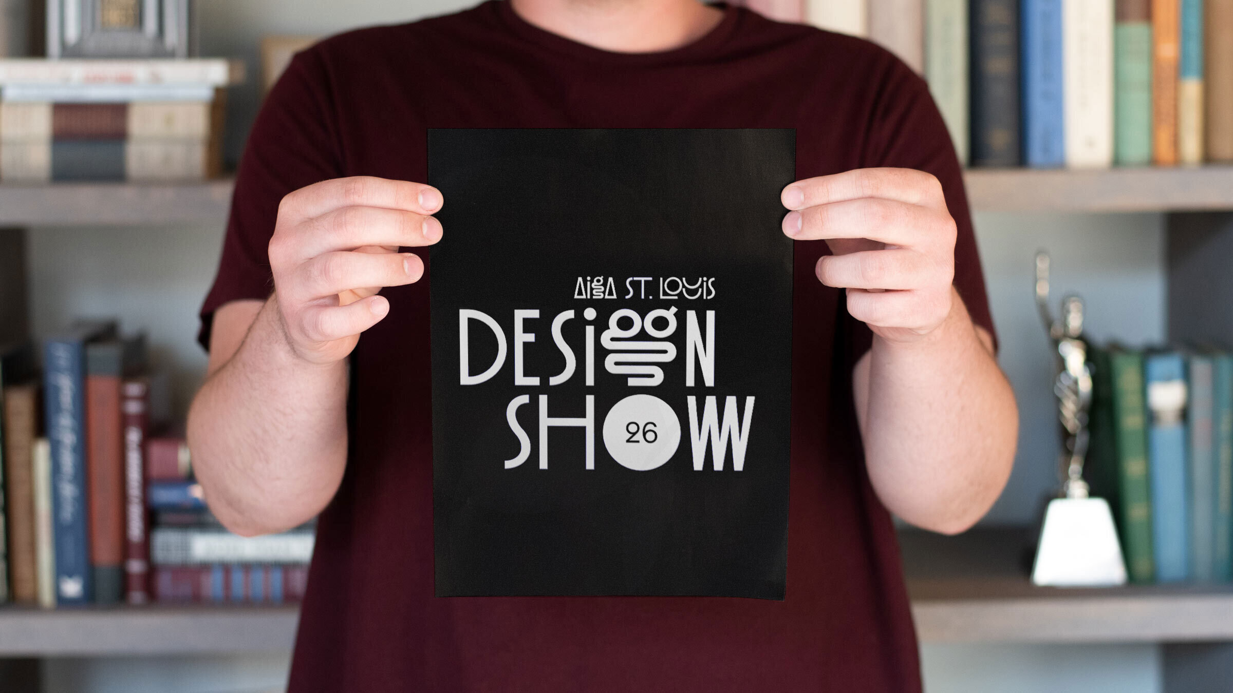 Atomicdust team member holds an AIGA St. Louis Design Show 2023 postcard