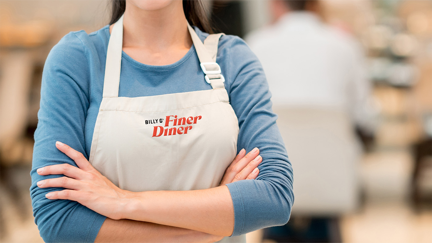A server wearing an apron with the Billy G's Finer Diner logo on it.