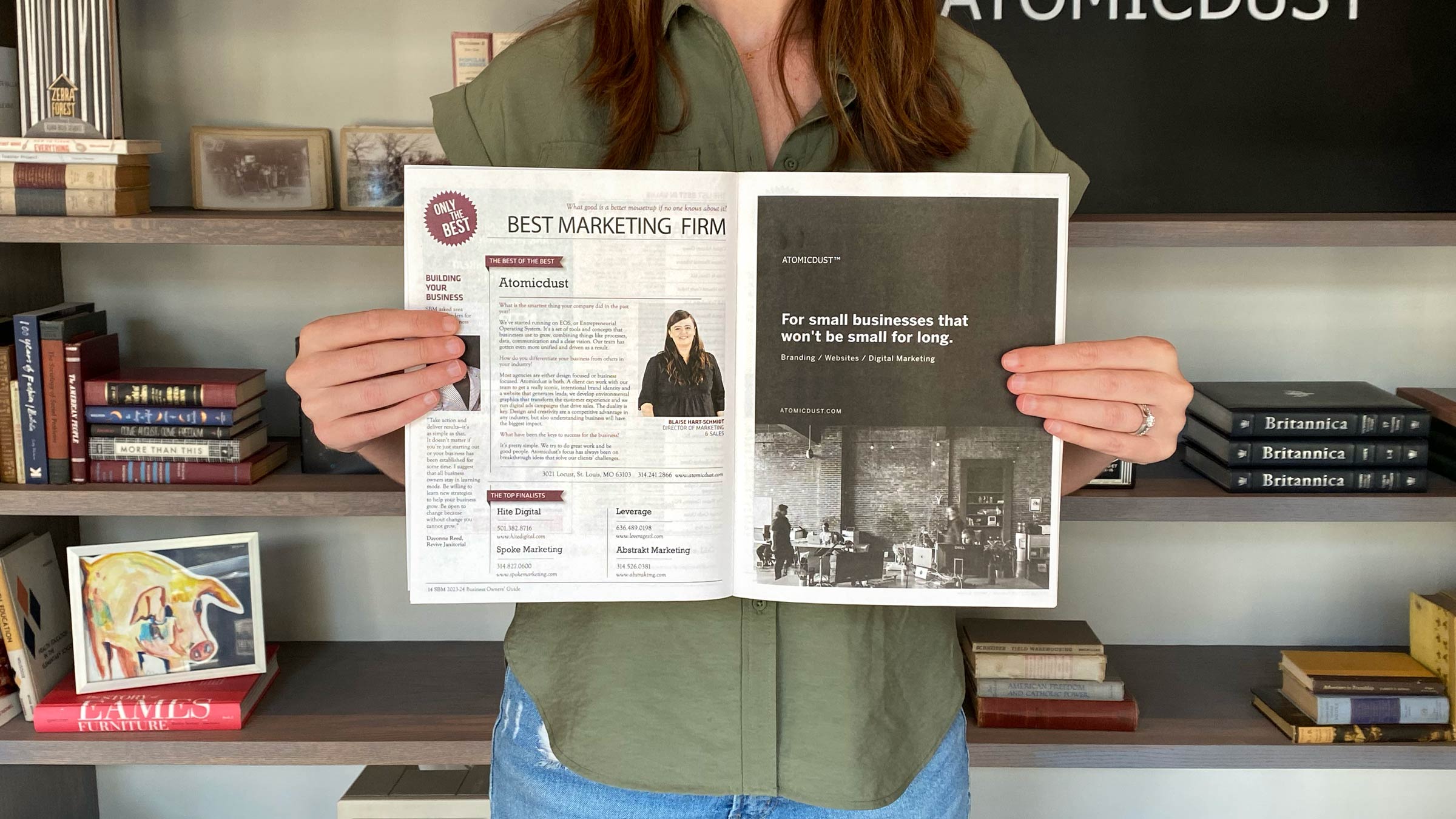 An Atomicdust team member holds a copy of Small Business Monthly with the article naming Atomicdust Best Marketing Firm for 2023