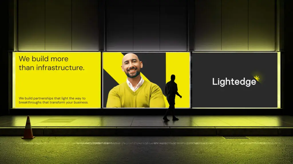 A person walks past a multi-panel digital billboard with tech infrastructure company Lightedge's new brand identity
