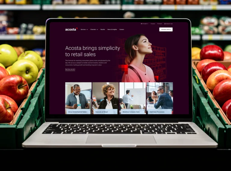 The Acosta website on a laptop in the produce section of a grocery store