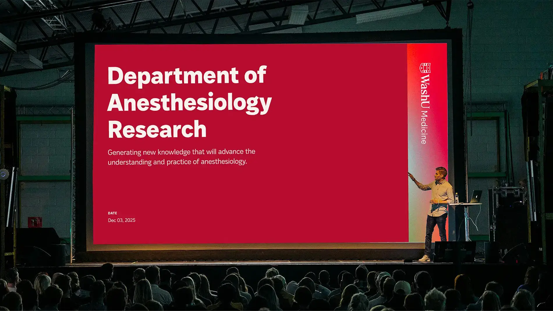 A speaker gives a talk at a conference with the WashU Medicine brand identity on a huge screen