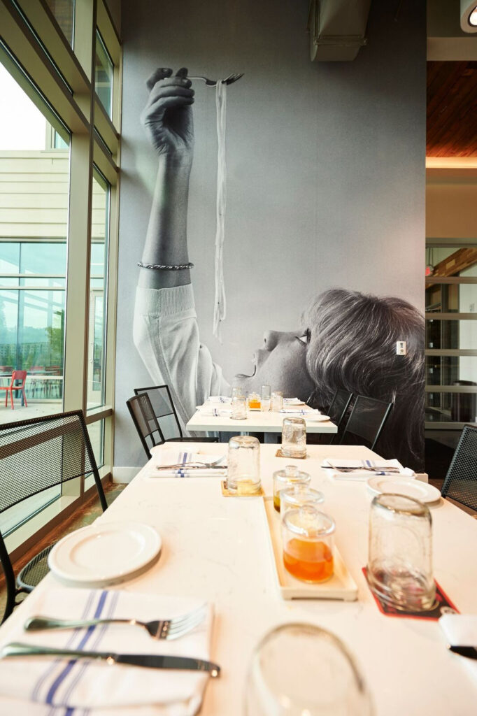 A large mural inside Pastaria Nashville shows a woman eating spaghetti