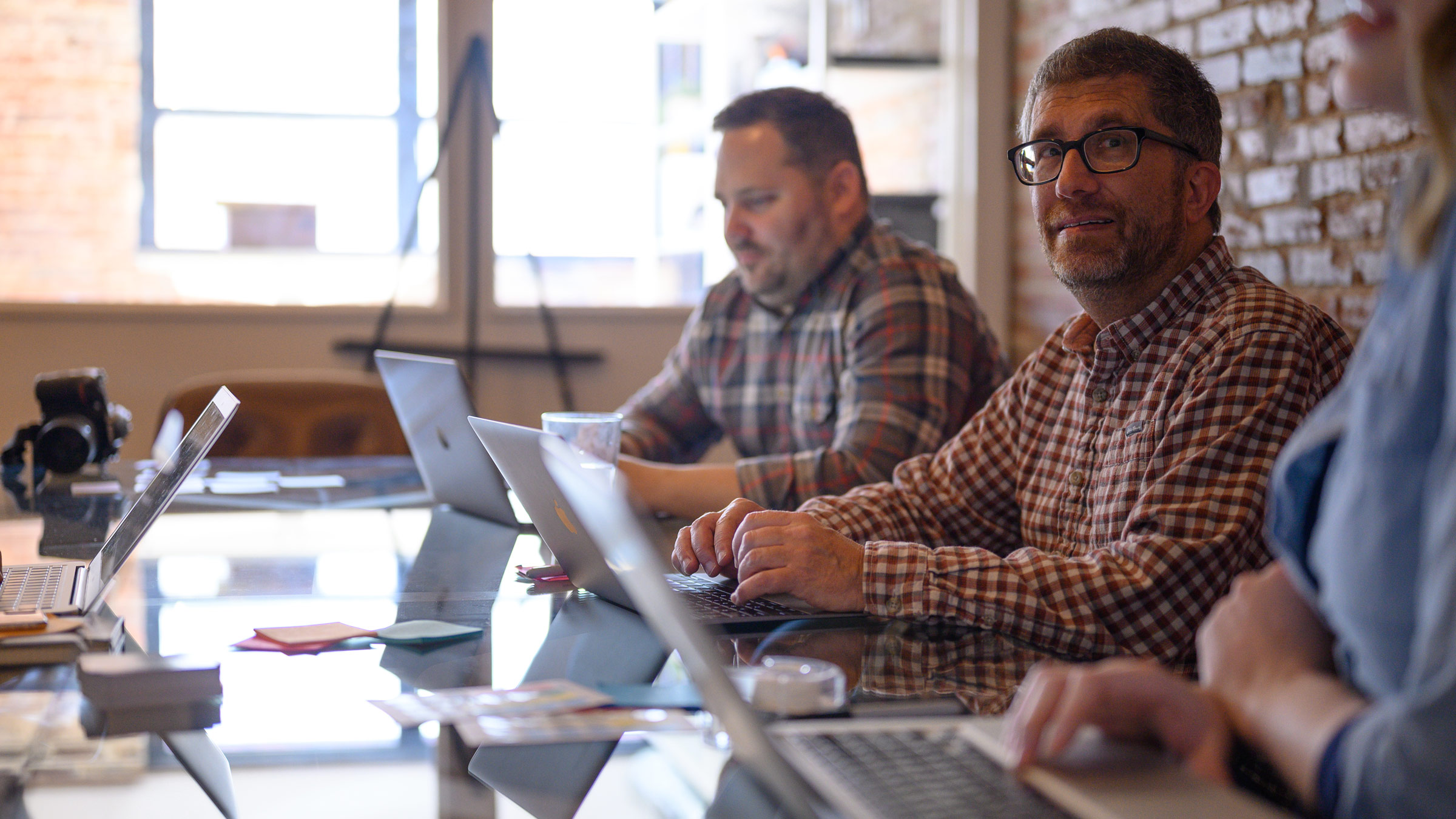 Atomicdust staff work on laptops during a meeting - Atomicdust was named one of the Best Marketing Firms in St. Louis by Small Business Monthly