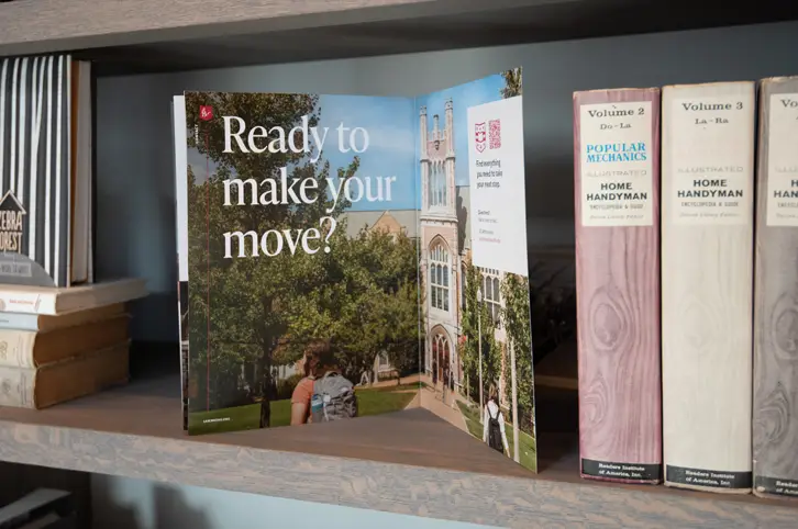 WashU Law marketing brochure opened on shelf displaying recruitment message ‘Ready to make your move?’ with campus photography and clean typography.