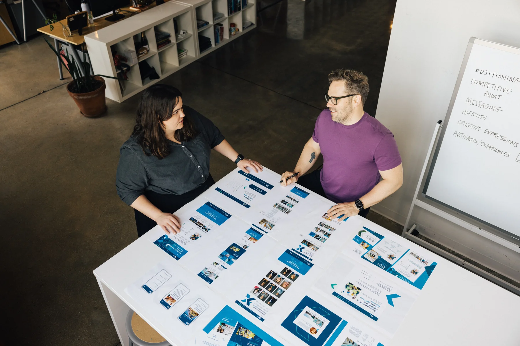 Atomicdust team in a workshop session reviewing positioning printouts at a table
