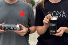 Atomicdust team members wearing 25th anniversary t-shirts and holding custom-labeled beers a client surprised us with for our party