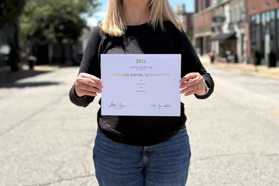 Atomicdust team members holds Graphic Design USA Award certificates