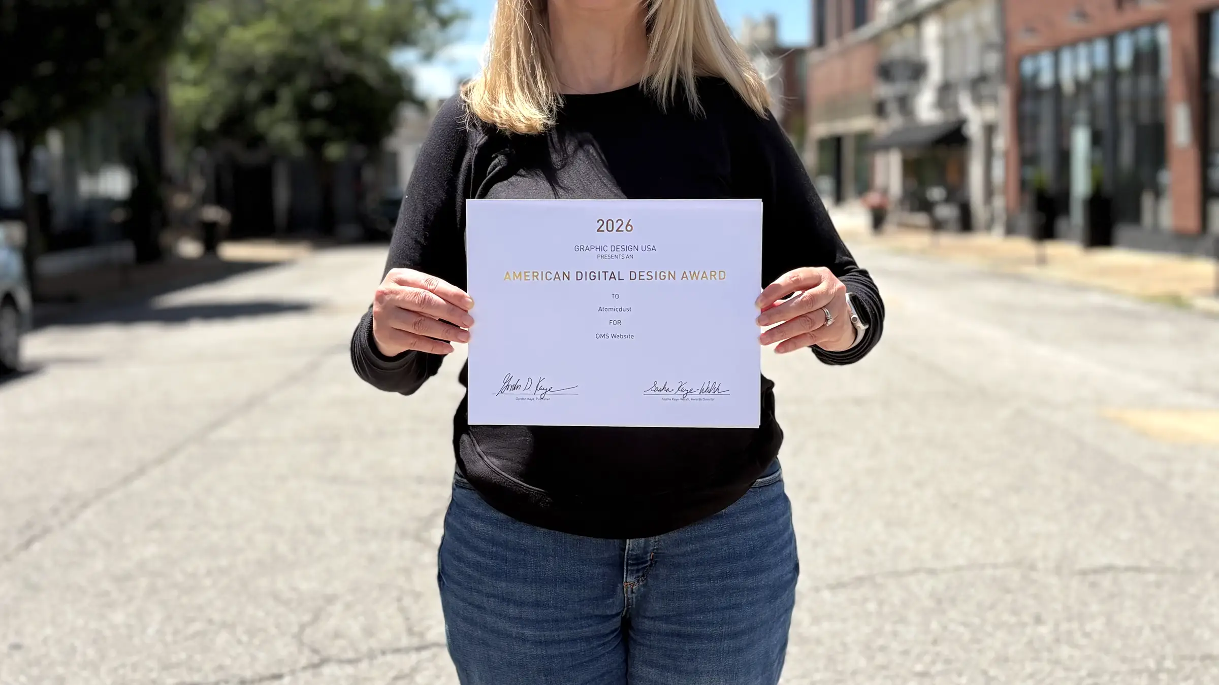 Atomicdust team members holds Graphic Design USA Award certificates