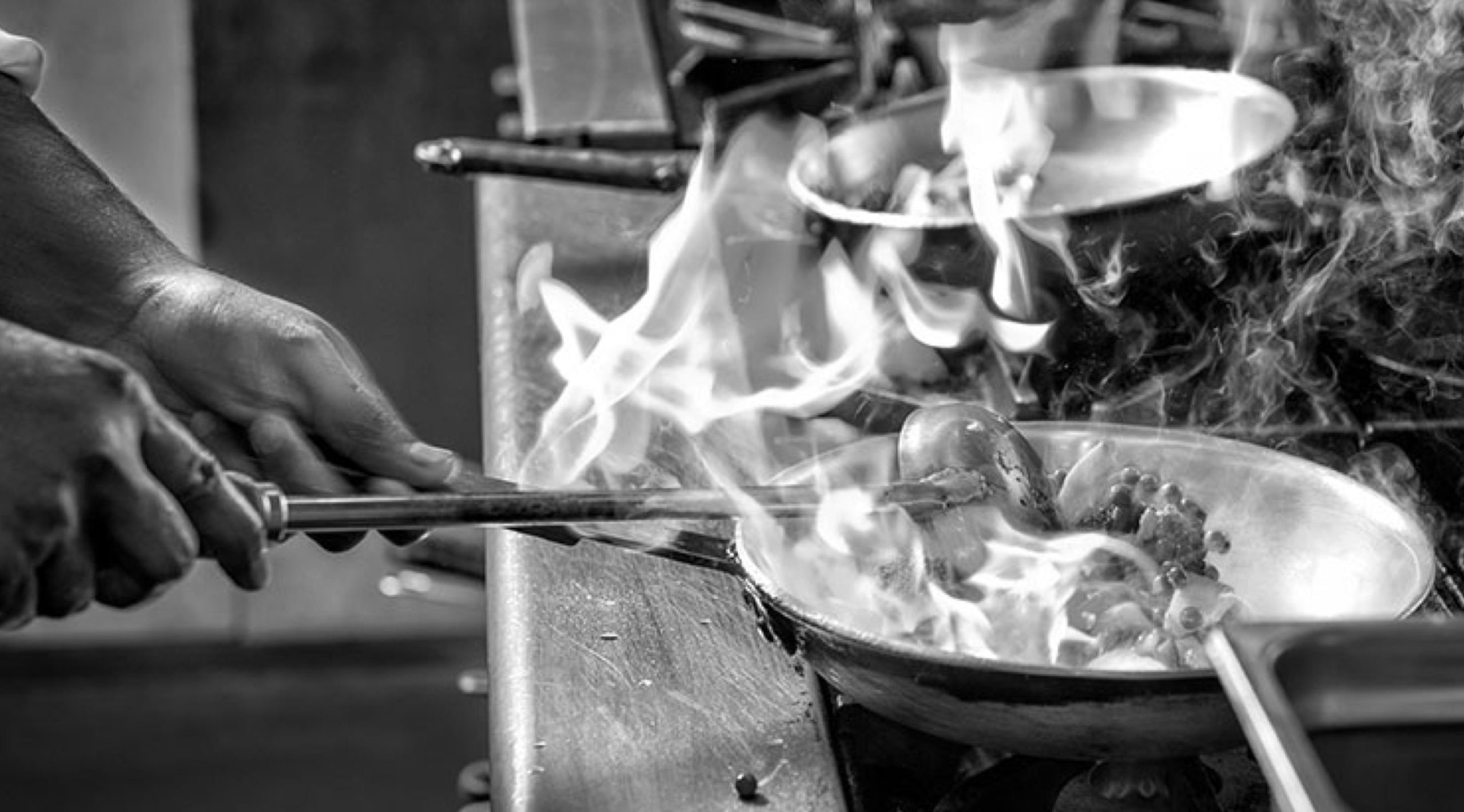 Black and white photo of hands cooking in a kitchen as part of Savoy's branding