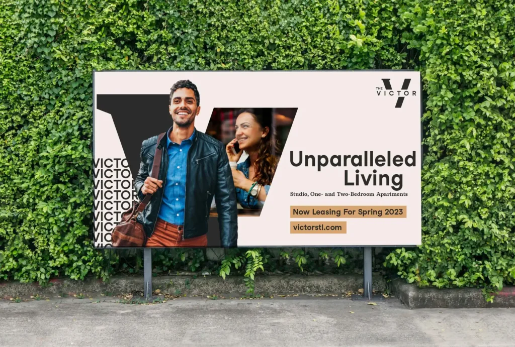 The Victor apartments billboard reading "Unparalleled Living" and "Now Leasing For Spring 2023" on green hedge