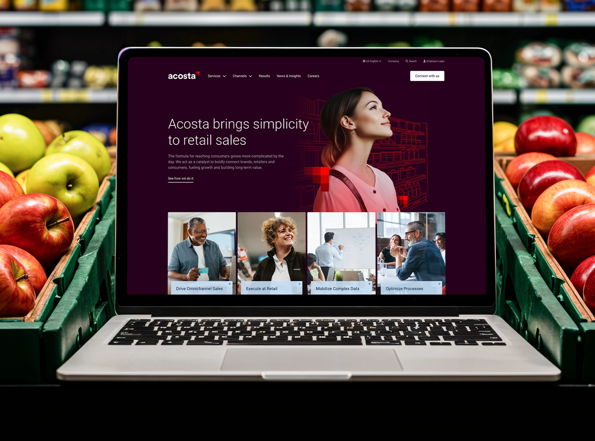 The Acosta website on a laptop in the produce section of a grocery store