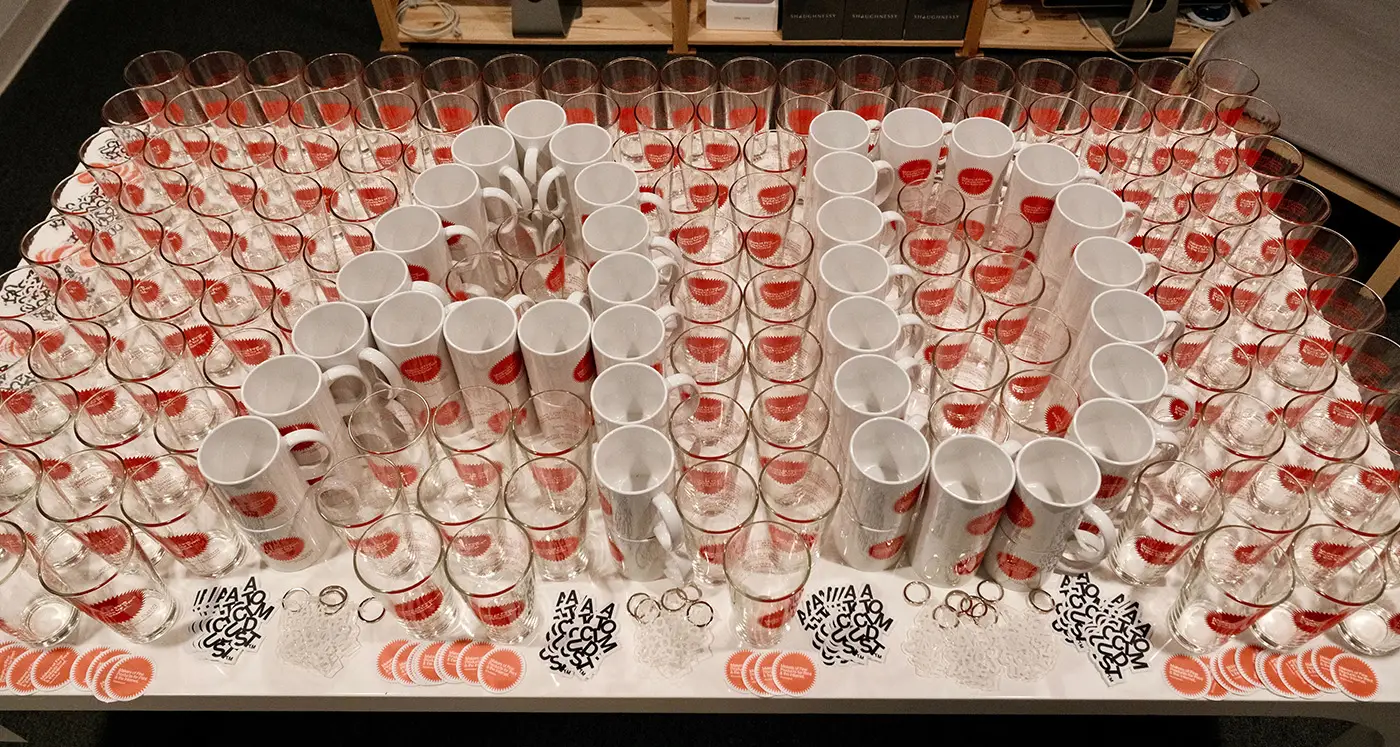 A table filled with glasses, mugs and stickers Atomicdust gave away at the anniversary party