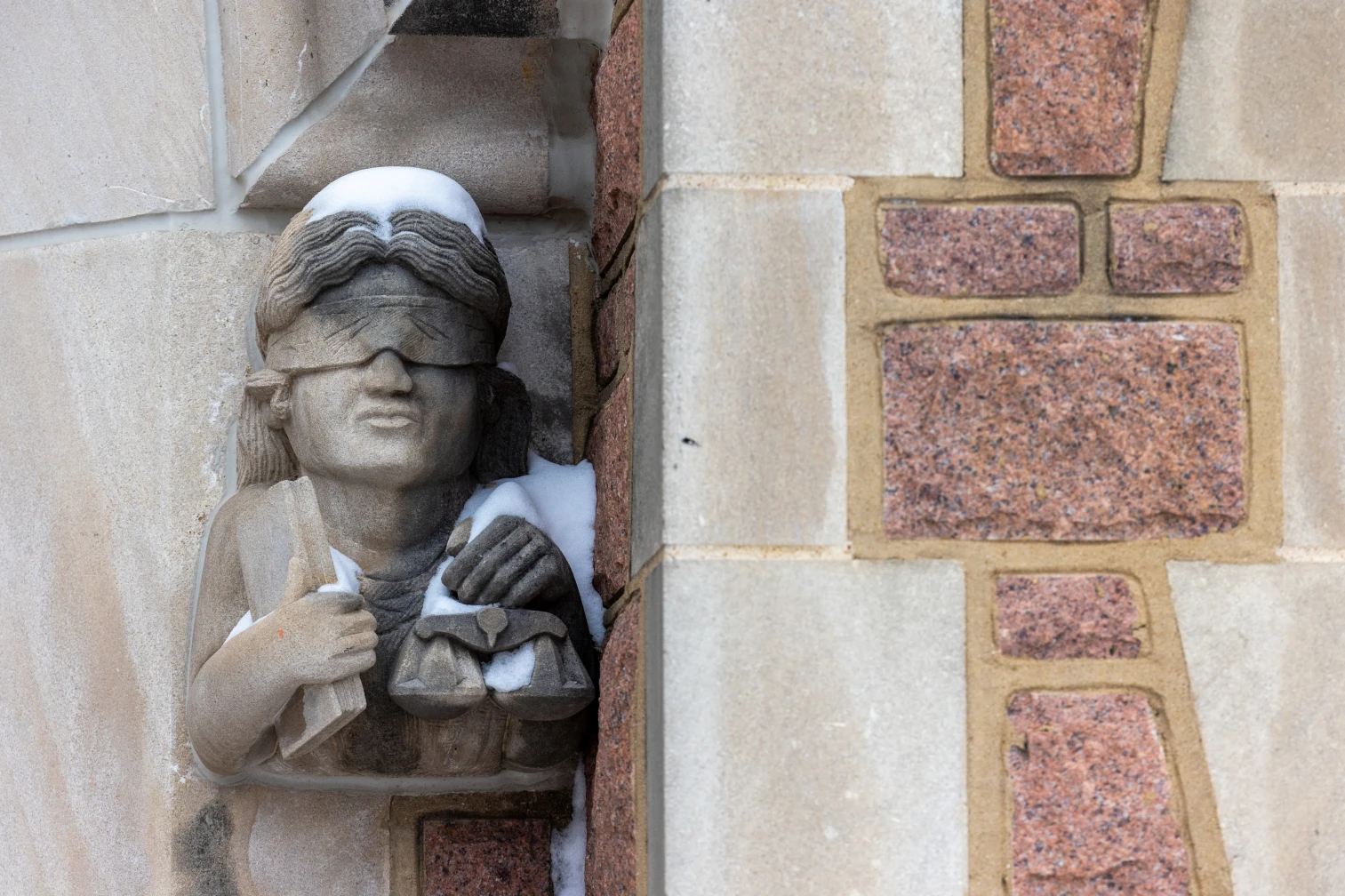 A stone carving of Lady Justice on a WashU Law building