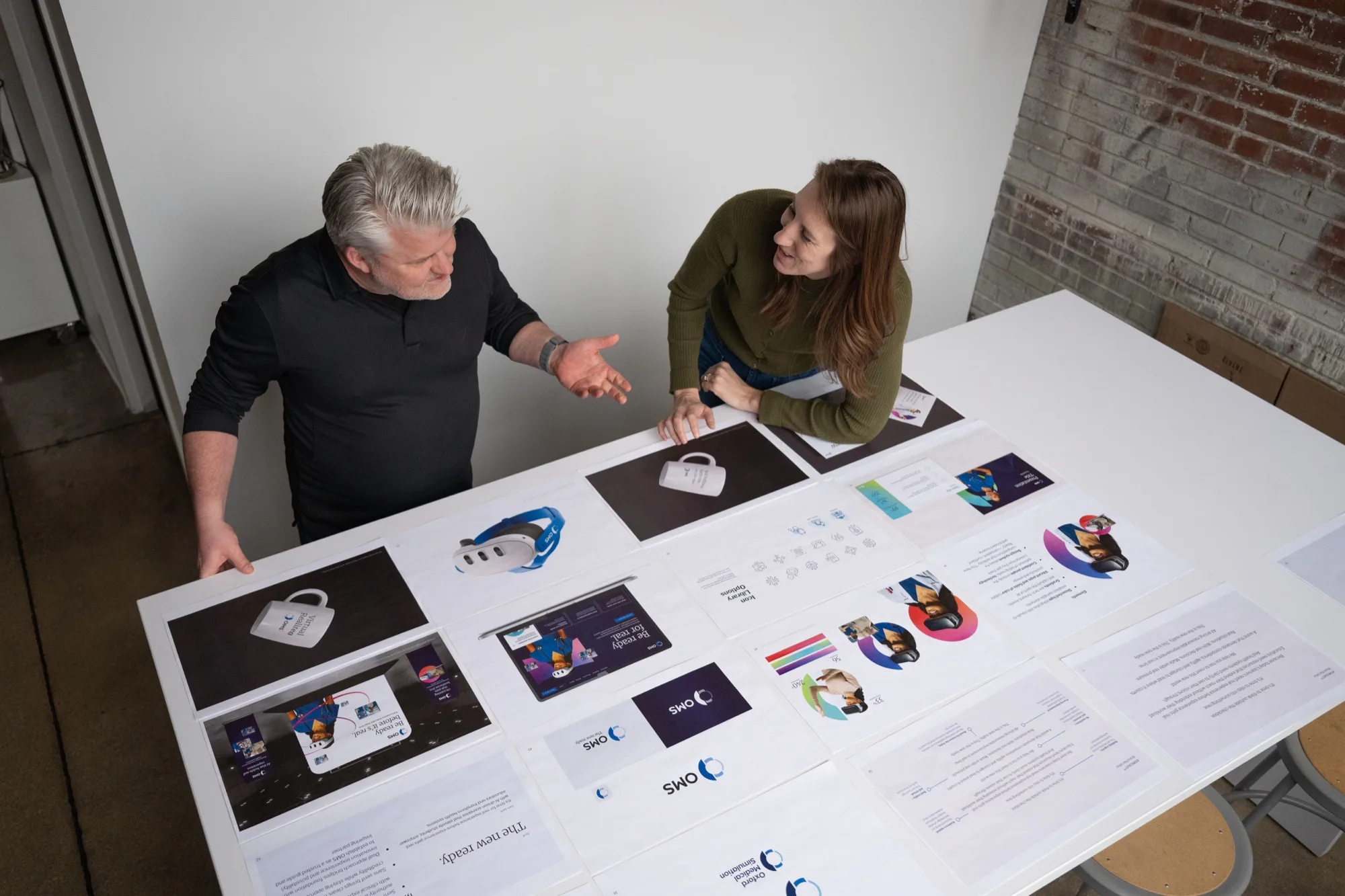 Atomicdust designers reviewing brand mockups on white table