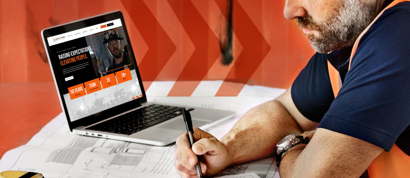 Hoist & Crane Service Group homepage on a laptop reading "Raising expectations. Elevating people." beside a technician reviewing drawings