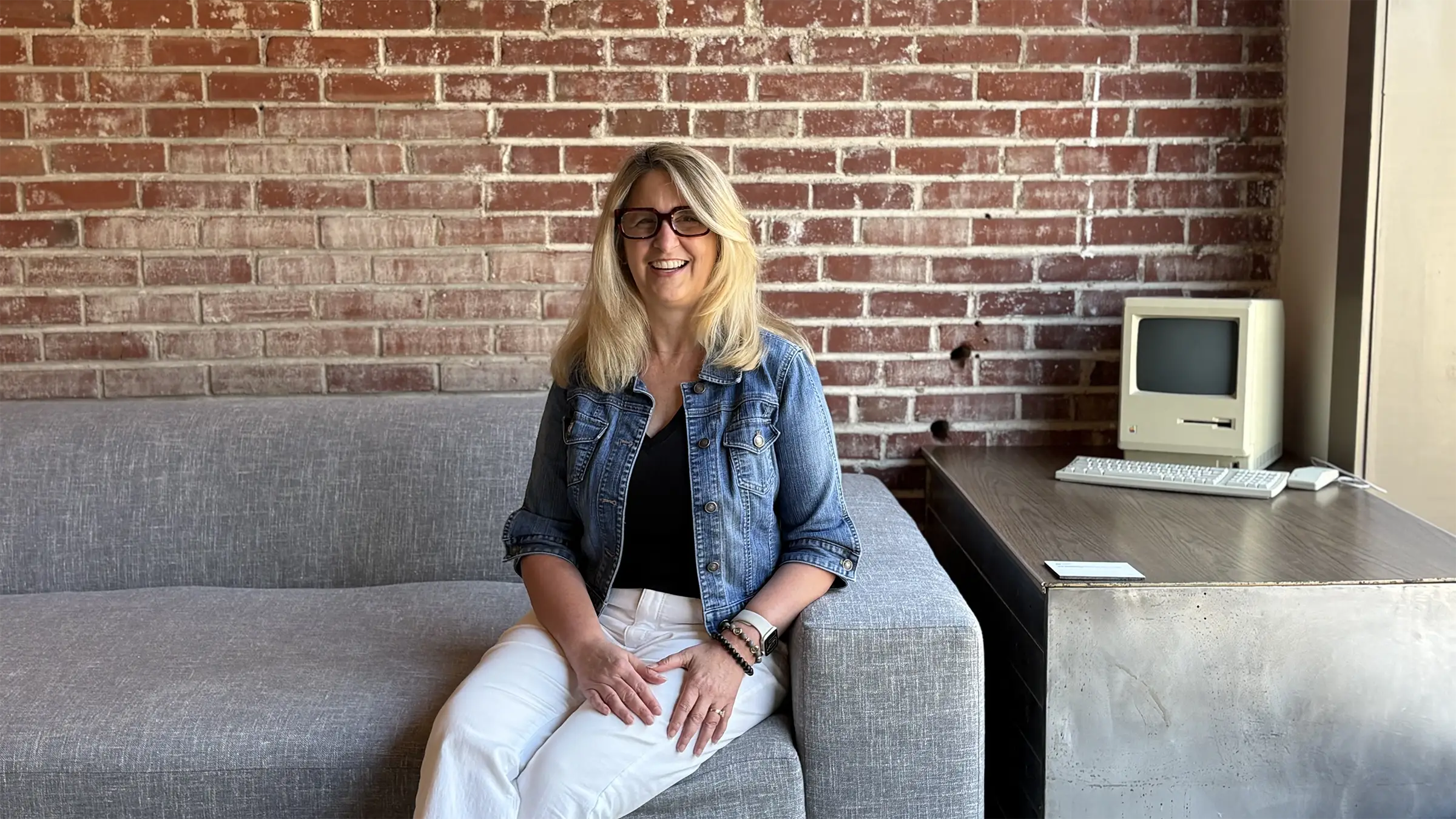 Nicholle Rosson, New Business Coordinator, on a couch in the Atomicdust office